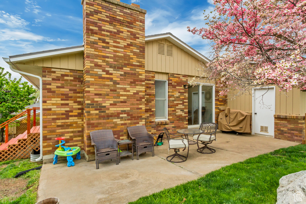 Rear view of house with brick siding, a patio, and a chimney