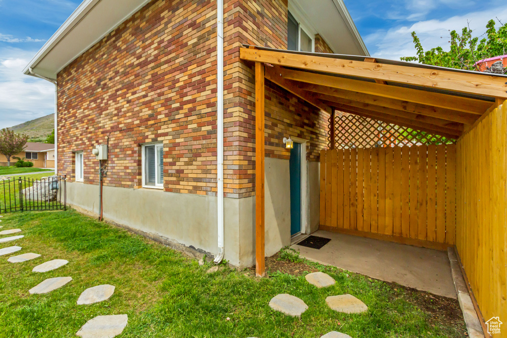 View of home's exterior with fence, a yard, and brick siding