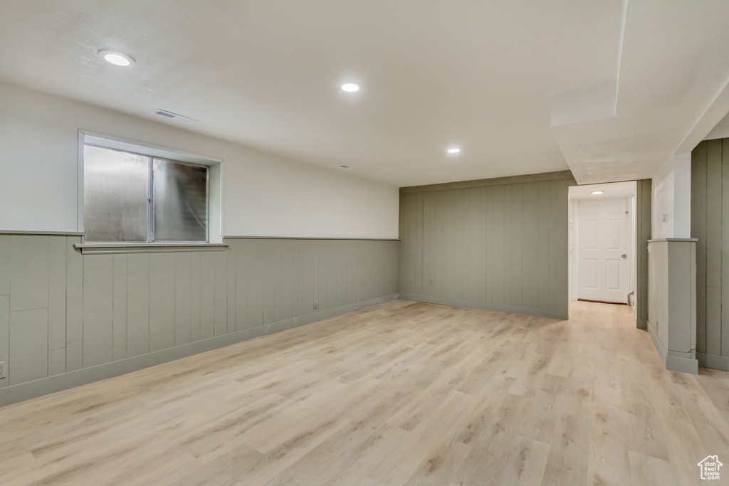 Finished below grade area featuring light wood-style floors, recessed lighting, a wainscoted wall, and wooden walls