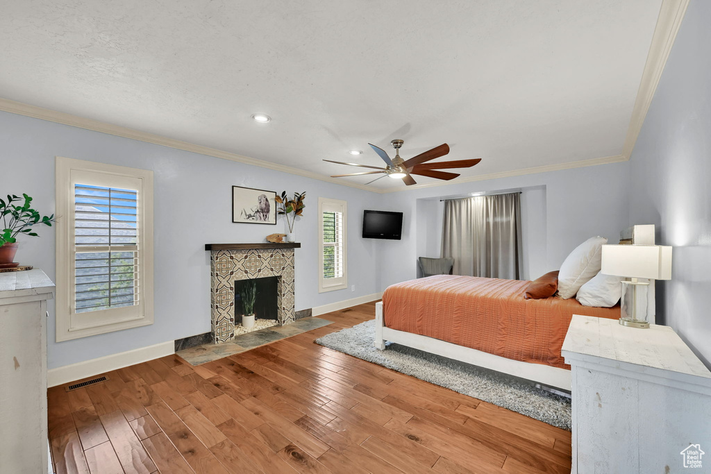 Bedroom with visible vents, baseboards, crown molding, and wood finished floors