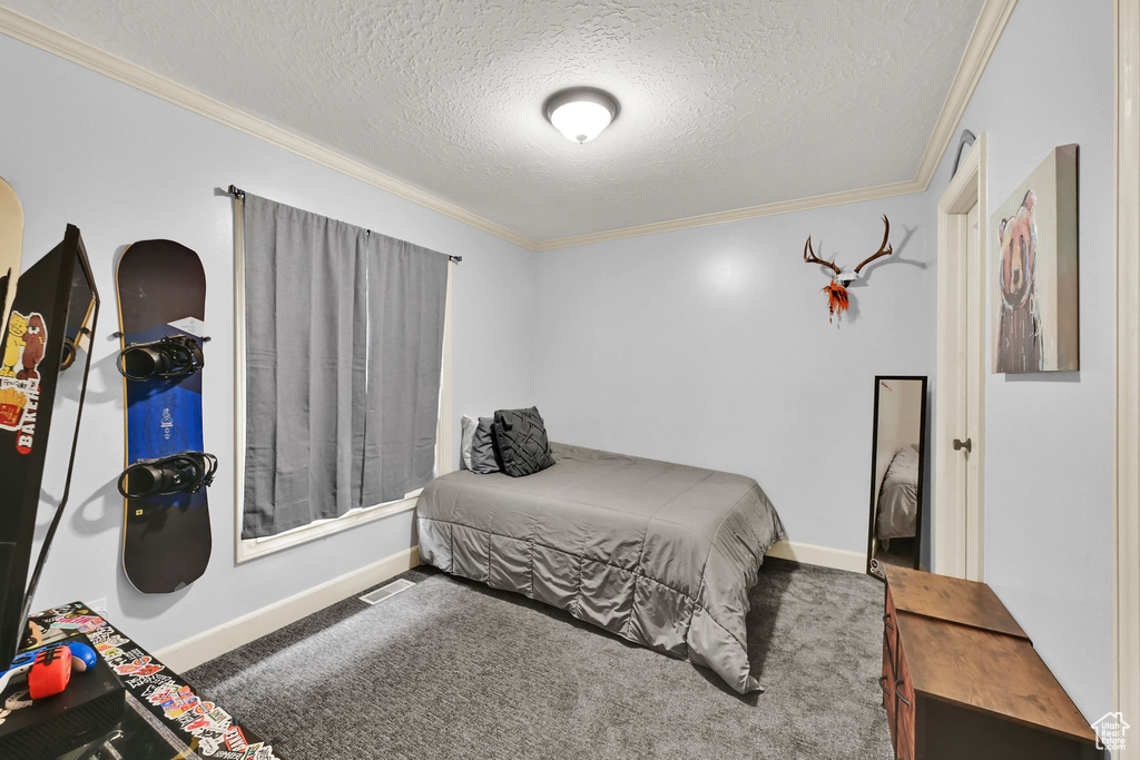 Bedroom with carpet floors, ornamental molding, and a textured ceiling