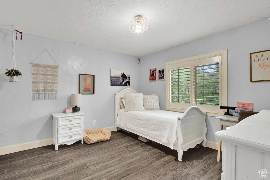 Bedroom featuring baseboards, a textured ceiling, and wood finished floors