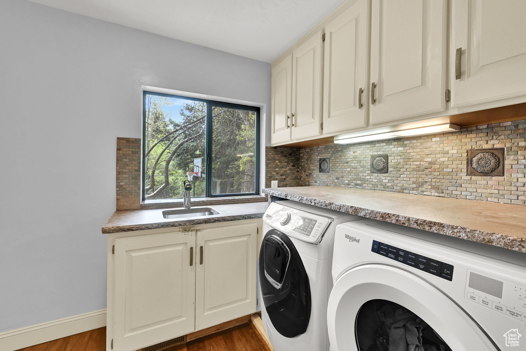 Laundry room featuring dark wood-type flooring, a sink, cabinet space, and independent washer and dryer