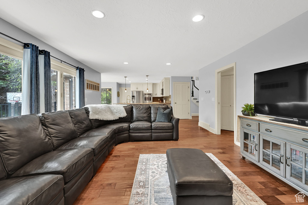 Living area with stairs, recessed lighting, baseboards, and wood finished floors