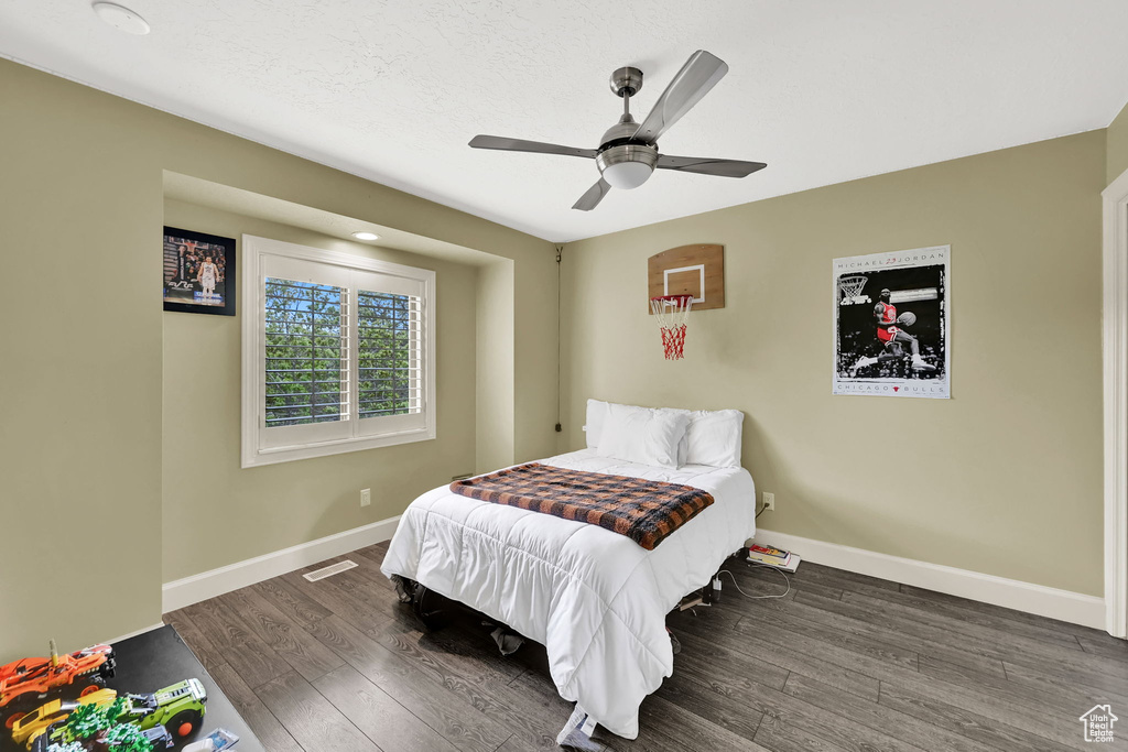 Bedroom with baseboards, a ceiling fan, wood finished floors, and visible vents