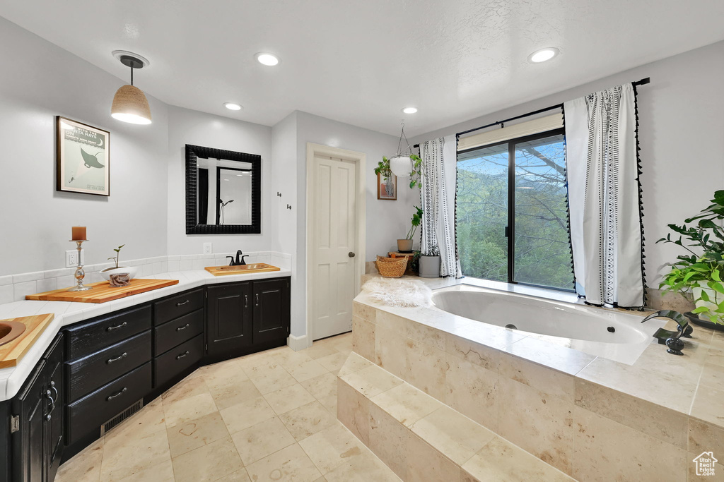 Full bath featuring recessed lighting, a sink, a bath, and double vanity