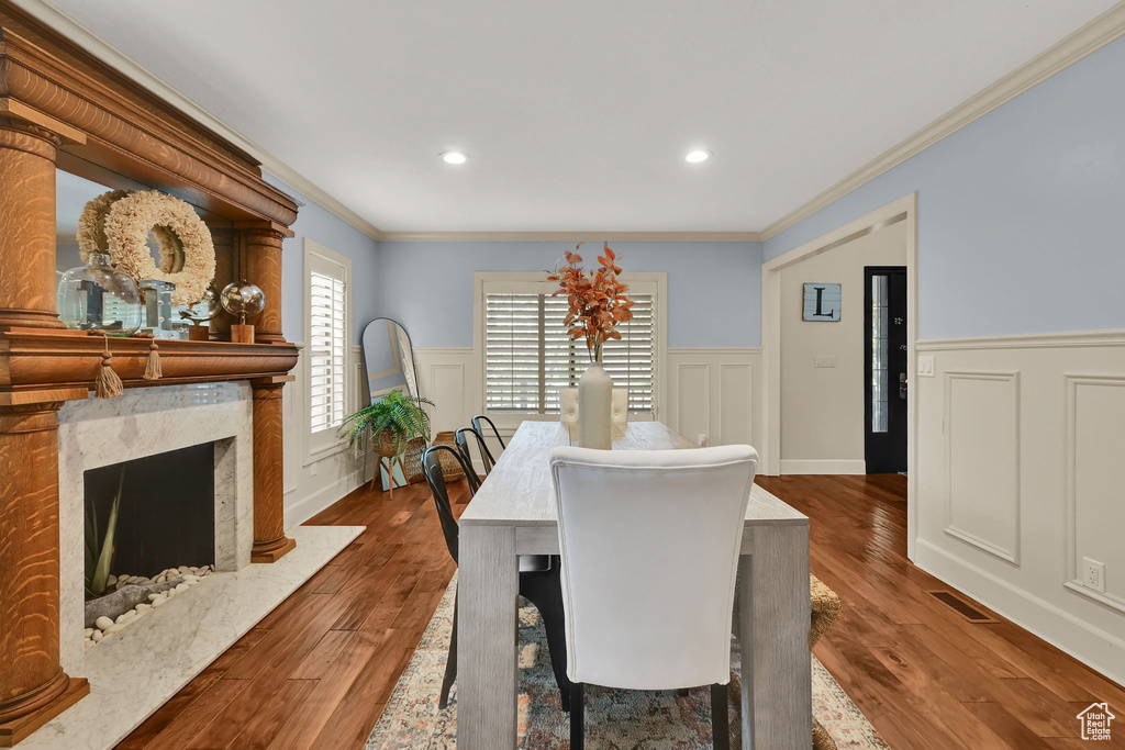 Dining space with visible vents, wainscoting, crown molding, and wood finished floors
