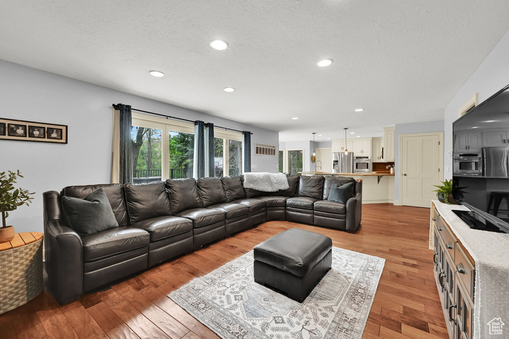 Living room featuring a textured ceiling, recessed lighting, and light wood-style flooring