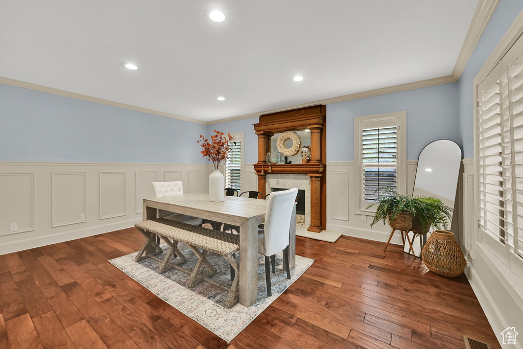 Dining space featuring crown molding, a wainscoted wall, visible vents, and dark wood-type flooring
