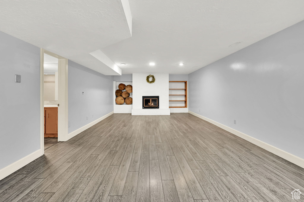Unfurnished living room with baseboards, a glass covered fireplace, and wood finished floors