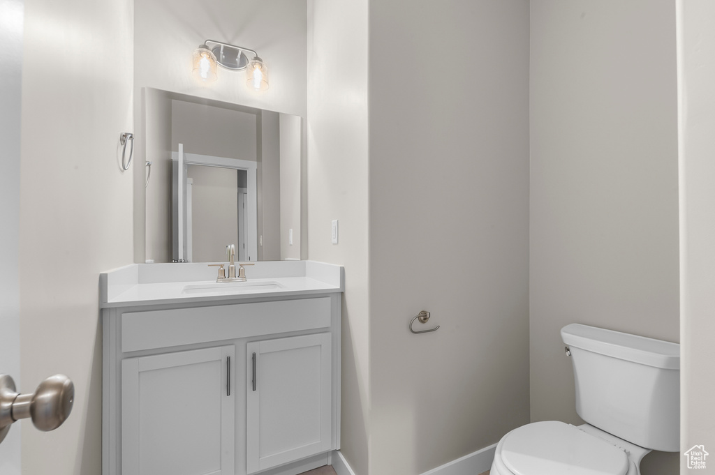 Half bathroom featuring vanity, baseboards, and toilet