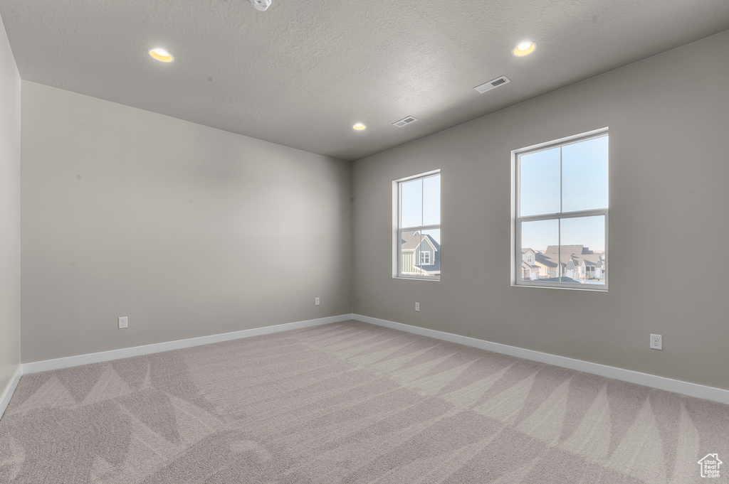 Empty room featuring light colored carpet, baseboards, visible vents, and recessed lighting