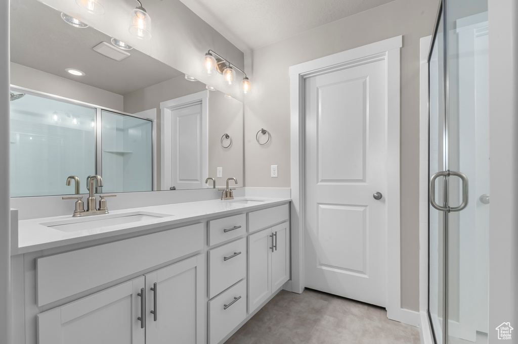 Bathroom with double vanity, a sink, and a stall shower