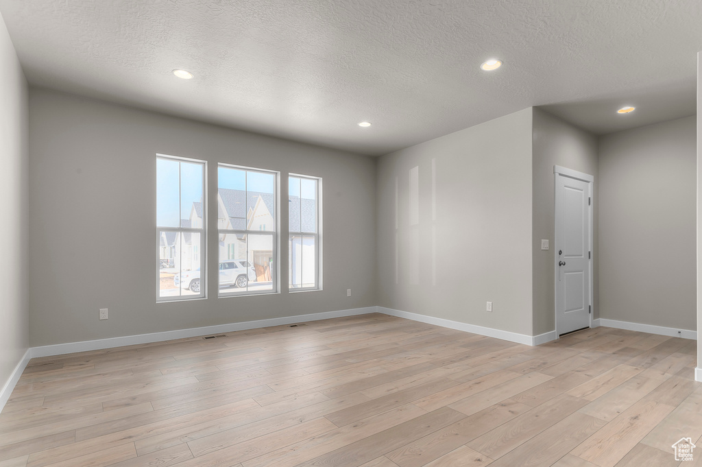 Empty room featuring recessed lighting, a textured ceiling, baseboards, and light wood finished floors