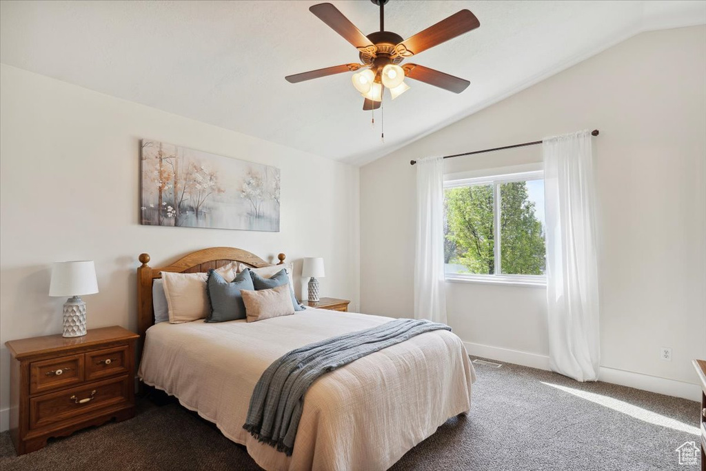 Carpeted bedroom with a ceiling fan, baseboards, vaulted ceiling, and visible vents