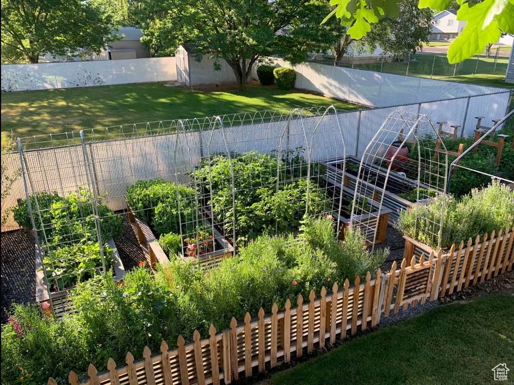 View of yard with a fenced backyard, a storage unit, an outdoor structure, and a garden