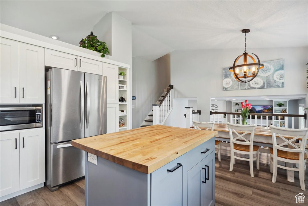 Kitchen with hanging light fixtures, a chandelier, wooden counters, dark wood finished floors, and stainless steel appliances
