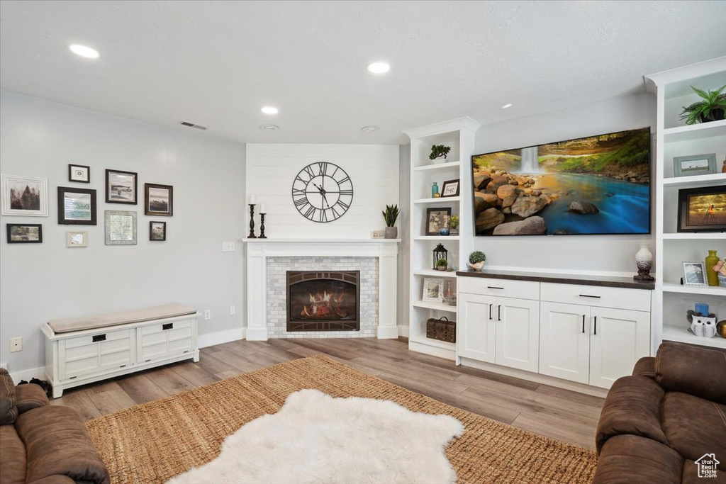 Living area with recessed lighting, wood finished floors, and a fireplace