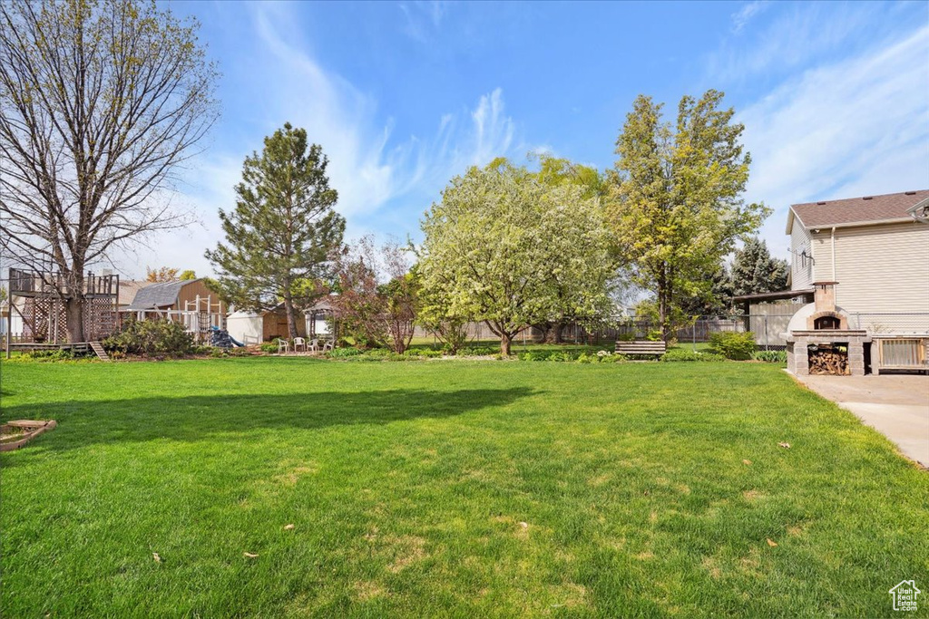 View of yard featuring an outdoor fireplace and fence