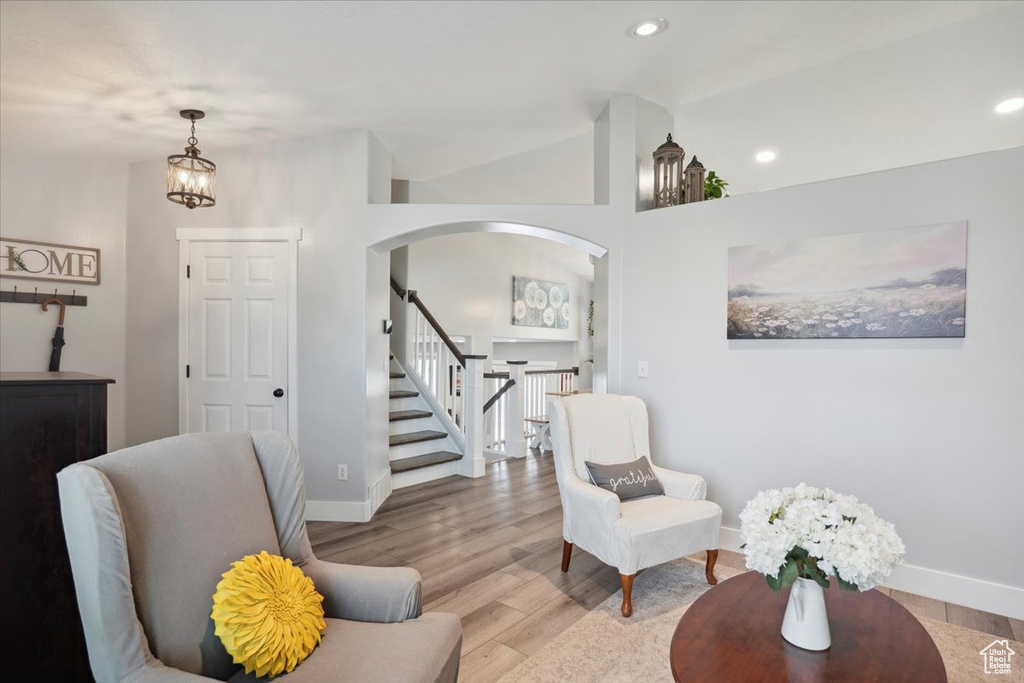 Living area featuring stairs, arched walkways, baseboards, and light wood finished floors