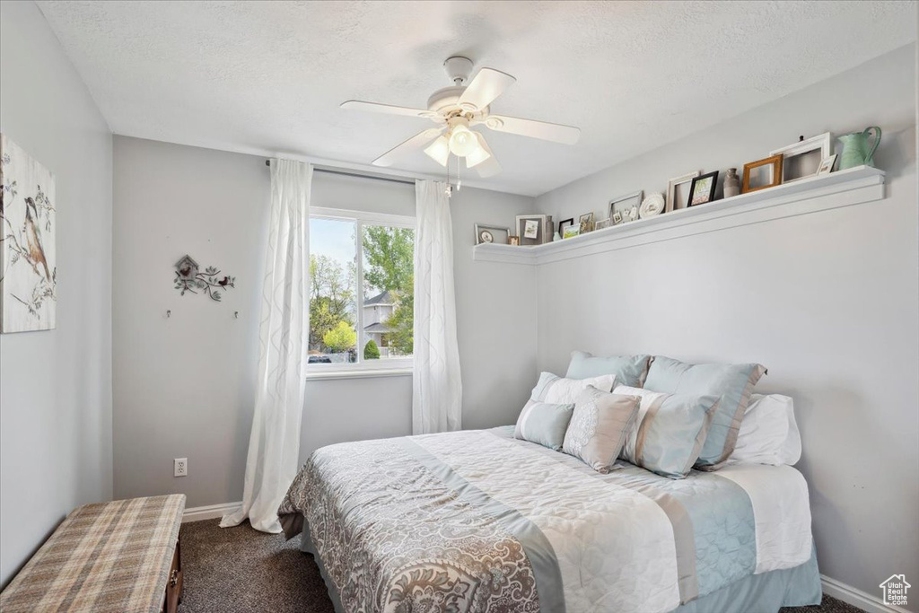 Carpeted bedroom with a ceiling fan, baseboards, and a textured ceiling