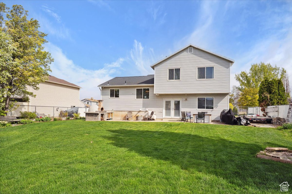 Rear view of house featuring a yard, a patio, fence, and french doors