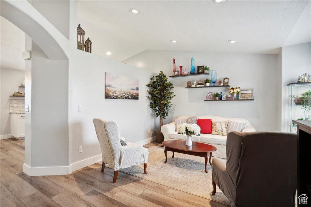Living room featuring light wood-type flooring, arched walkways, baseboards, and recessed lighting
