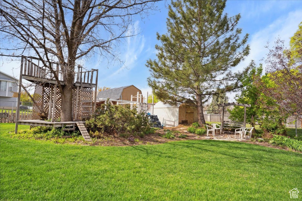 View of yard featuring fence, an outbuilding, stairway, and a wooden deck