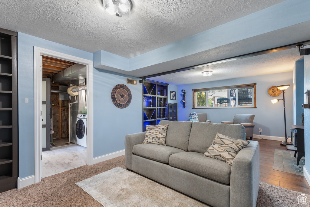 Living room featuring baseboards, a textured ceiling, and washer / dryer