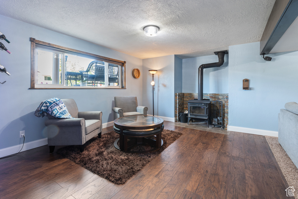Living area featuring baseboards, a wood stove, hardwood / wood-style flooring, and a textured ceiling