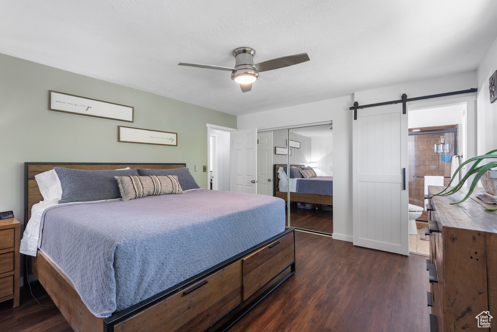 Bedroom with a closet, baseboards, a barn door, a ceiling fan, and dark wood finished floors