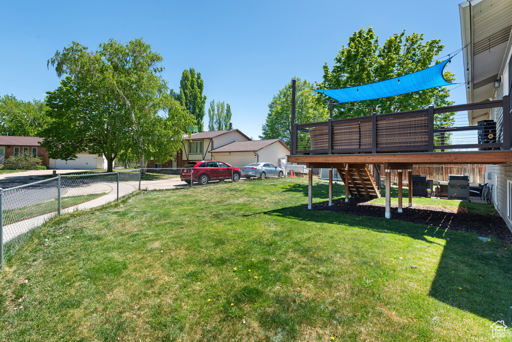 View of yard featuring fence, a wooden deck, and stairs