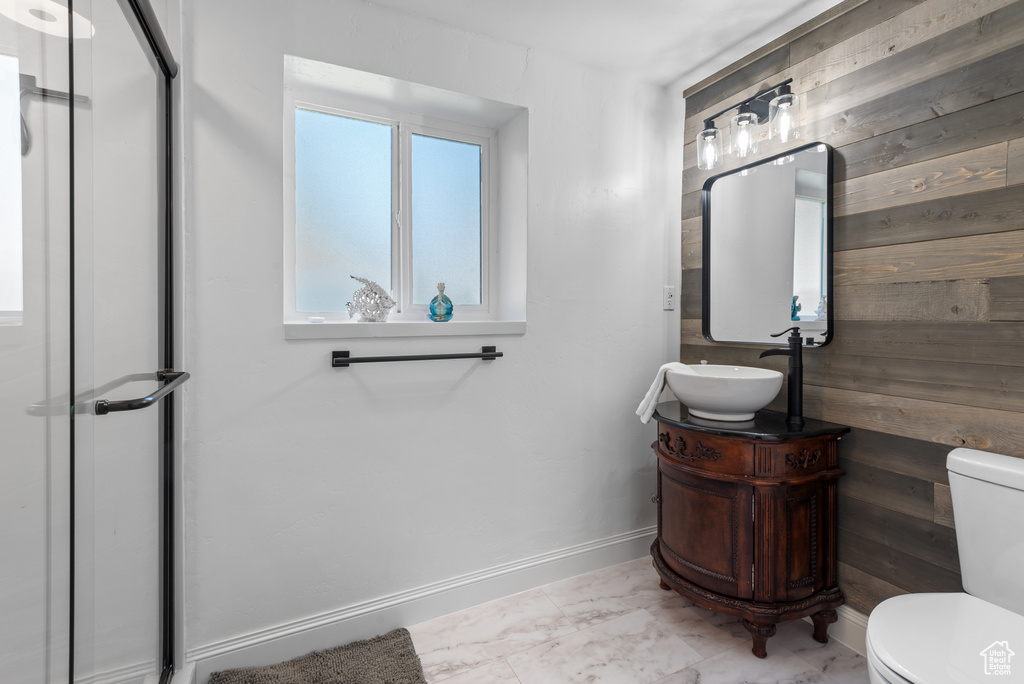 Bathroom featuring wood walls, vanity, and toilet