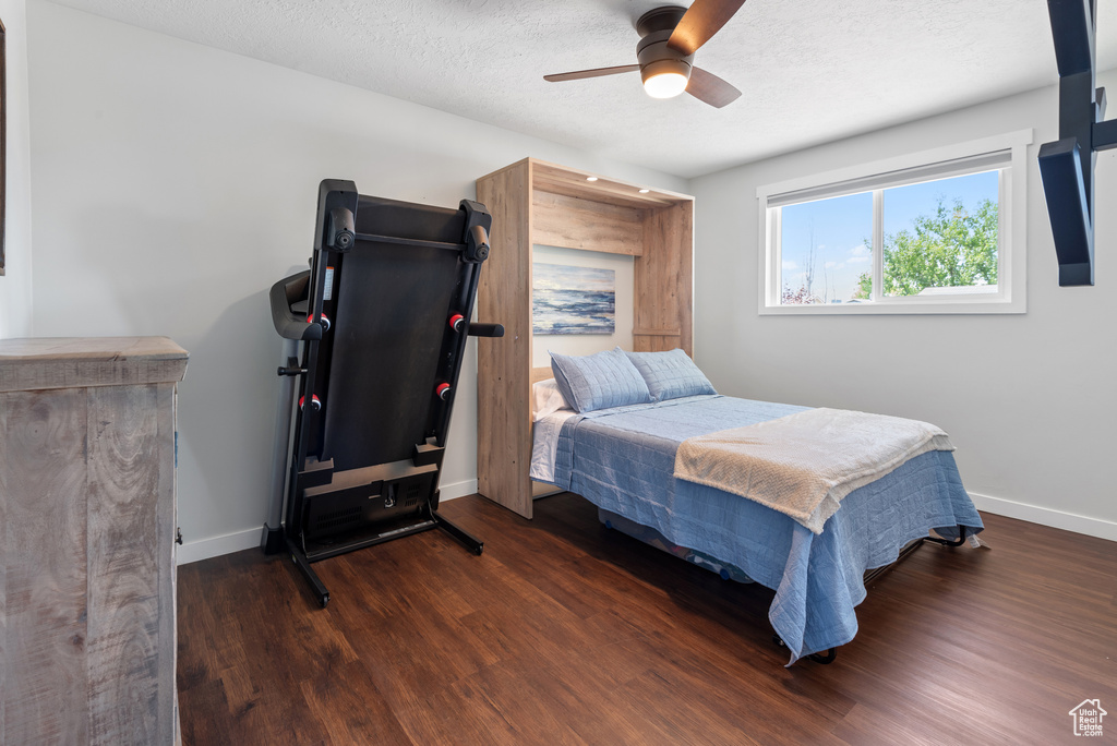 Bedroom featuring baseboards, a ceiling fan, a textured ceiling, and wood finished floors