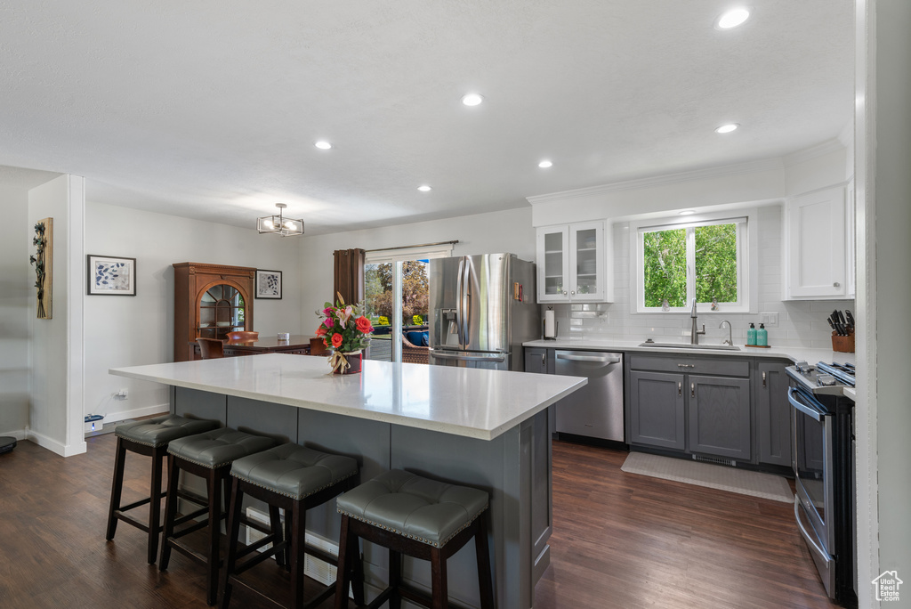 Kitchen with a kitchen island, a breakfast bar area, light countertops, a sink, and stainless steel appliances