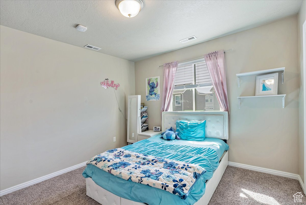 Bedroom with a textured ceiling, baseboards, visible vents, and carpet