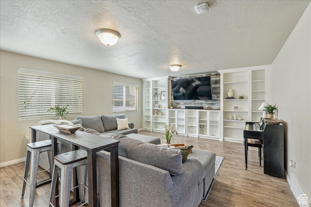 Living area featuring baseboards, a textured ceiling, and wood finished floors