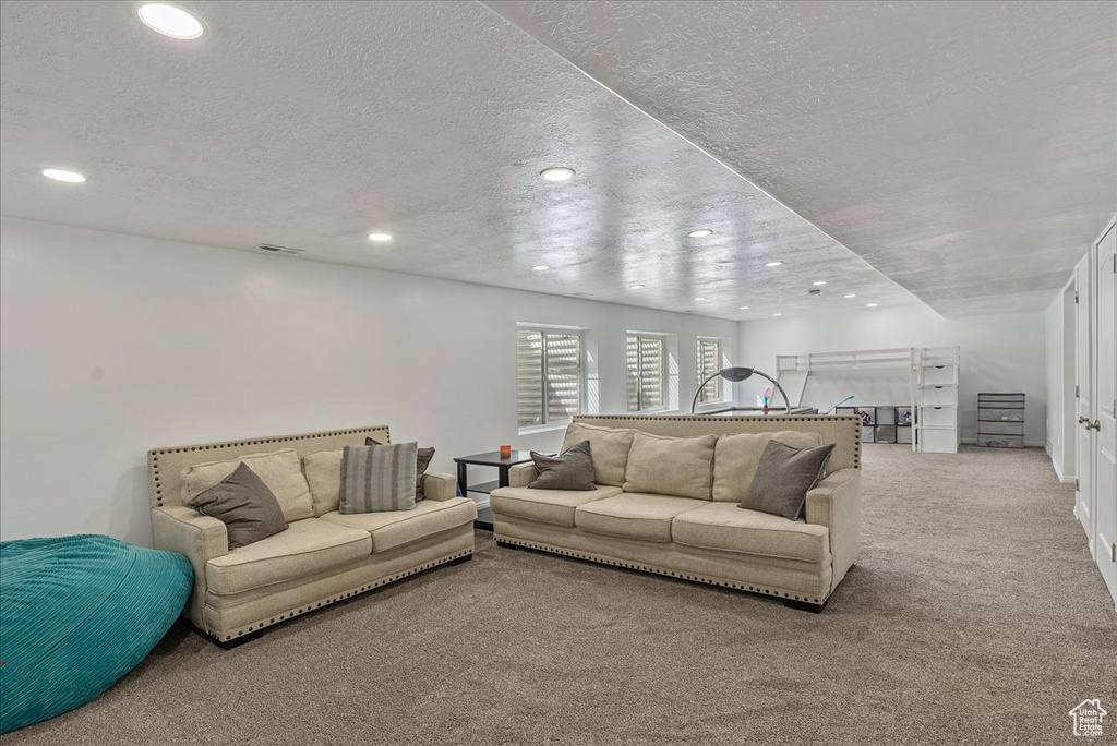 Carpeted living area featuring recessed lighting, a textured ceiling, and visible vents