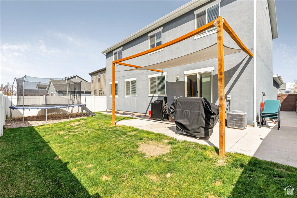 Rear view of house with a fenced backyard, a trampoline, and a patio area