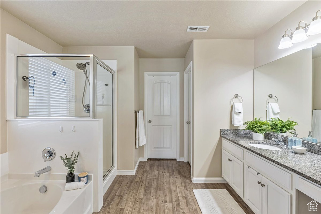 Full bath featuring vanity, wood finished floors, visible vents, a garden tub, and a stall shower