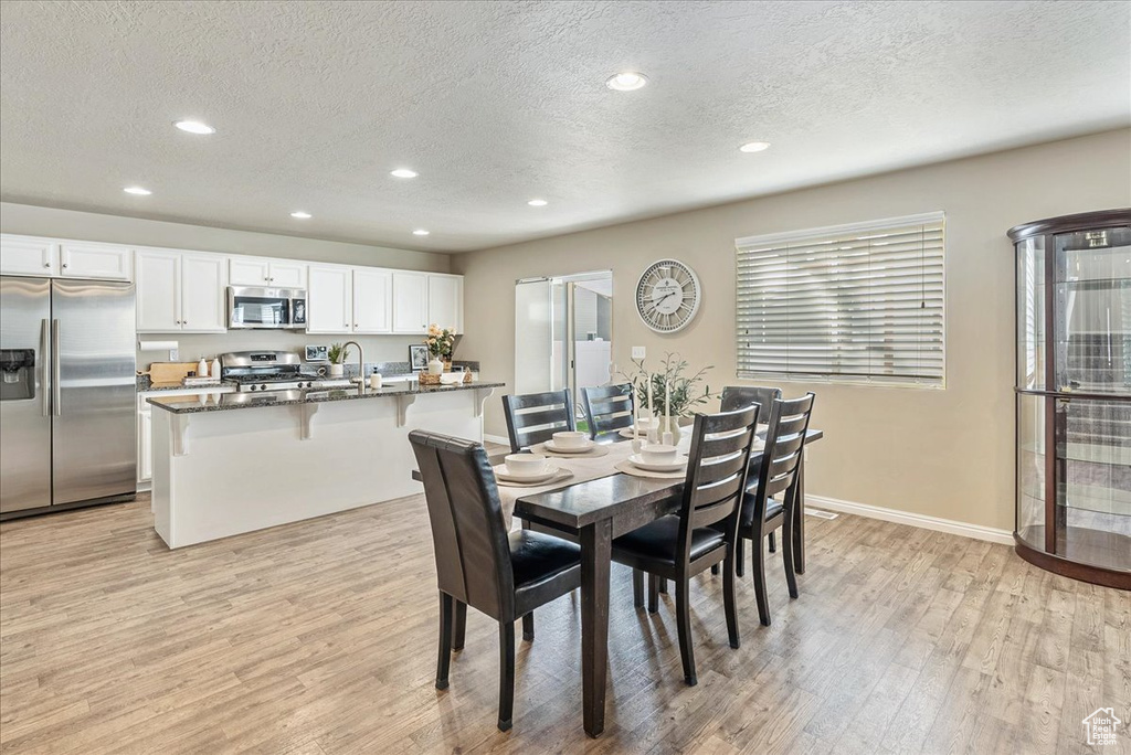 Dining area featuring baseboards, recessed lighting, a textured ceiling, and light wood-style flooring