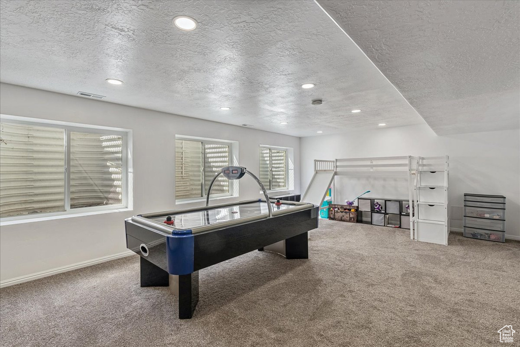 Recreation room featuring carpet flooring, recessed lighting, a textured ceiling, and visible vents