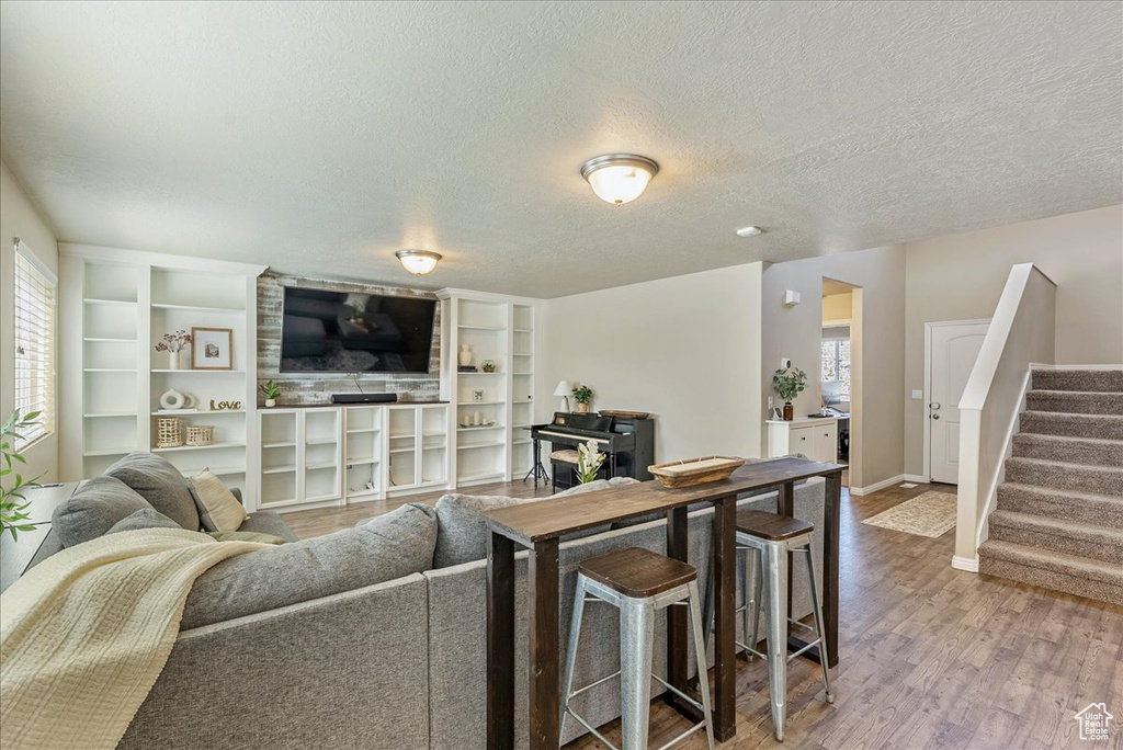 Living area featuring baseboards, a textured ceiling, stairs, and wood finished floors