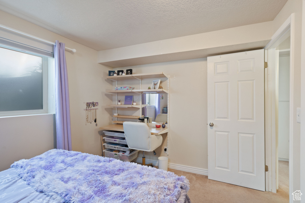 Carpeted bedroom featuring a textured ceiling and baseboards