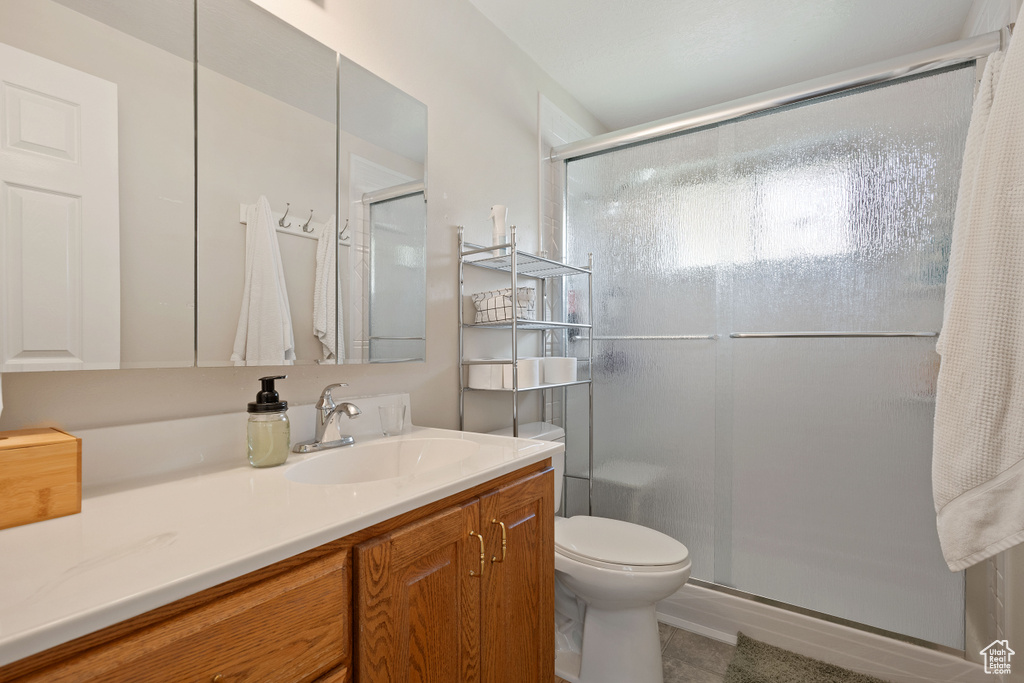 Bathroom featuring vanity, tile patterned floors, a shower stall, and toilet
