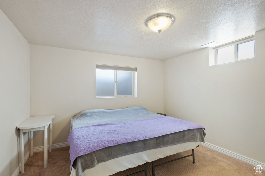 Carpeted bedroom featuring baseboards and a textured ceiling