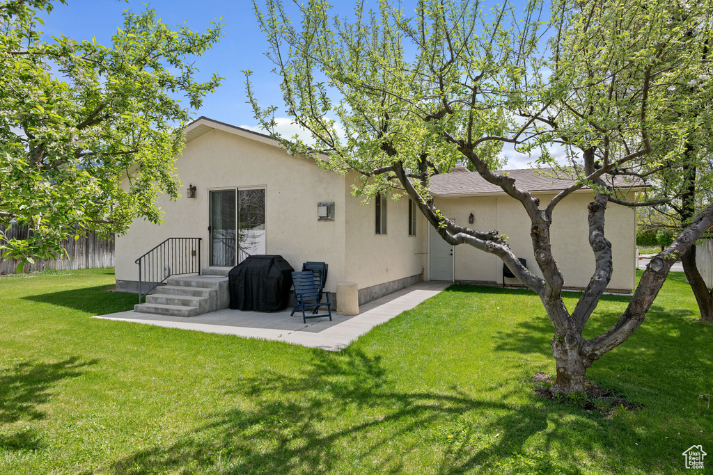 Back of house featuring stucco siding and a yard