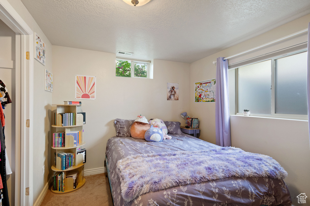 Bedroom with baseboards, carpet, a textured ceiling, and visible vents
