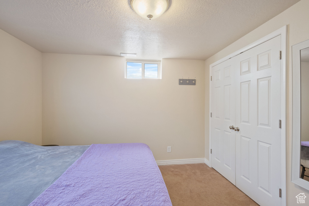 Bedroom featuring baseboards, a textured ceiling, and light colored carpet