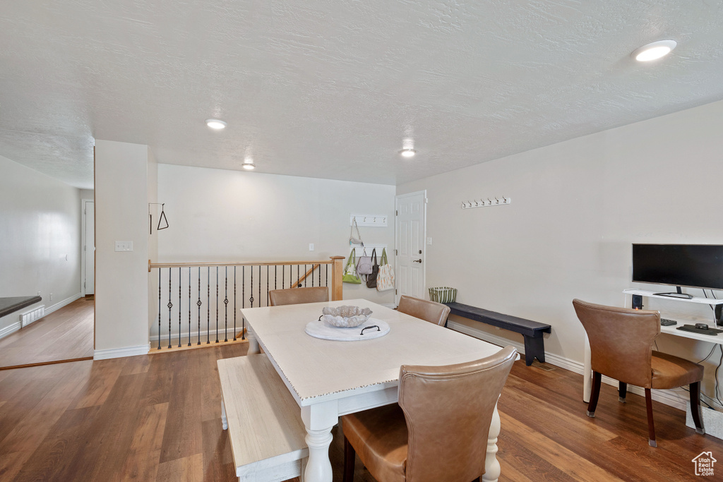 Dining area featuring a textured ceiling, baseboards, and dark wood-type flooring